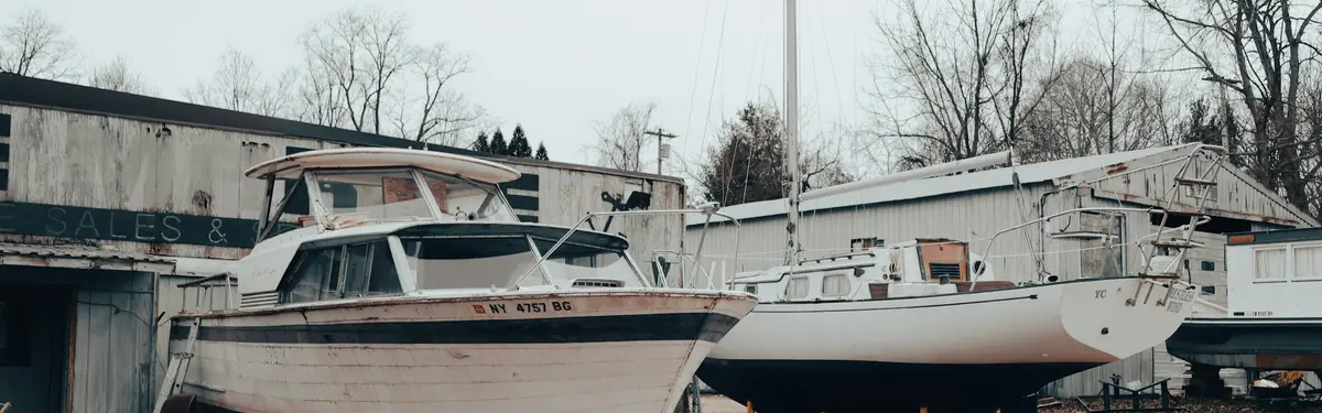 Two boats sit on dry land in front of a building.